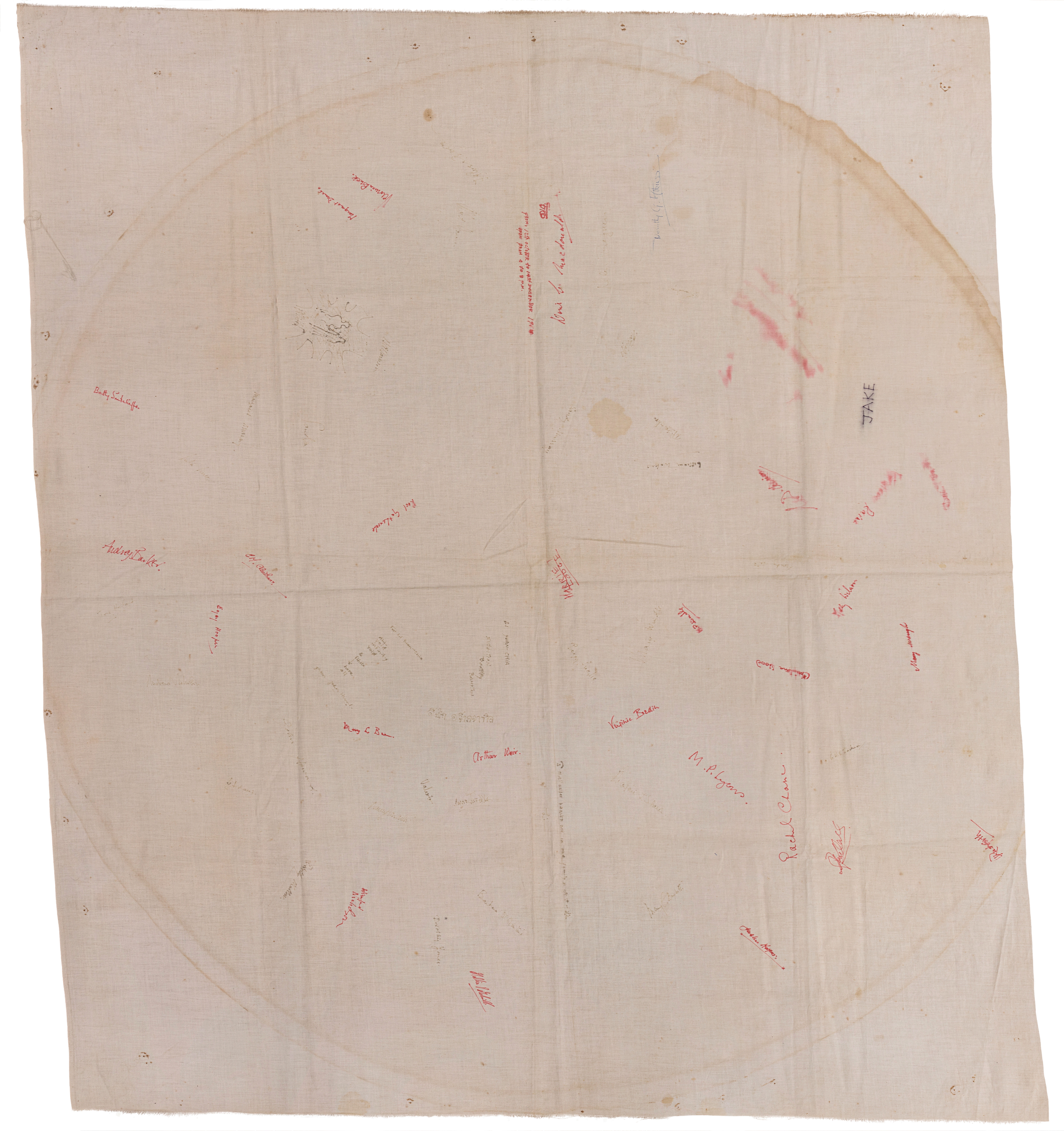 Tablecloth. A white cloth is signed with about thirty-five names or inscriptions in red or black. Some are blurred as if by water. Most are not legible, save an all-caps “Jake” near the top right.